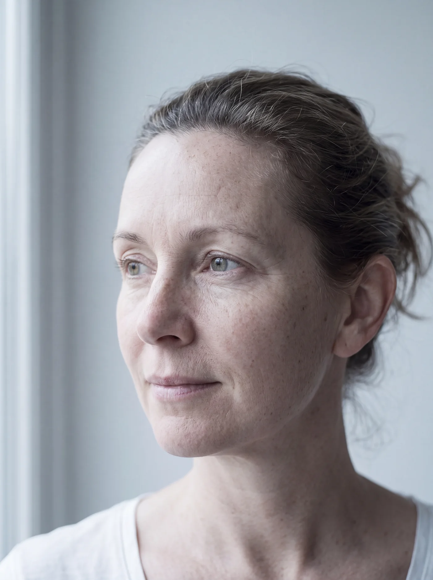 A woman of about fifty with natural, even skin by a window