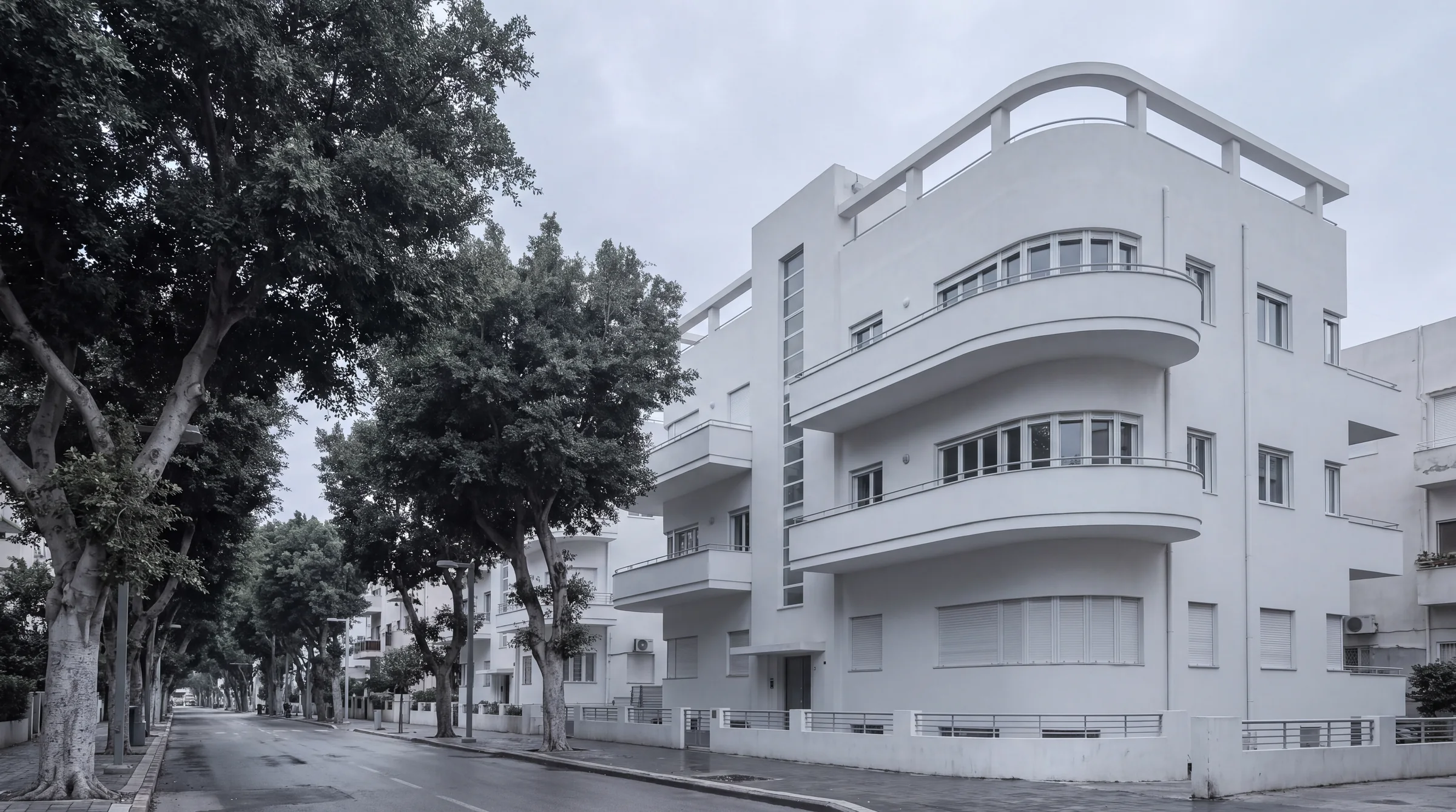 A white 1930s building on a tree-lined boulevard