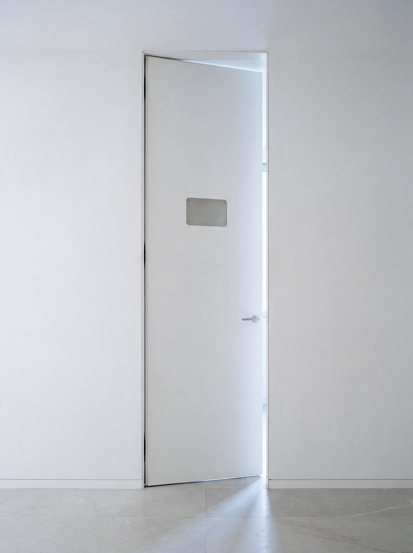A white door ajar with a blank steel name plate