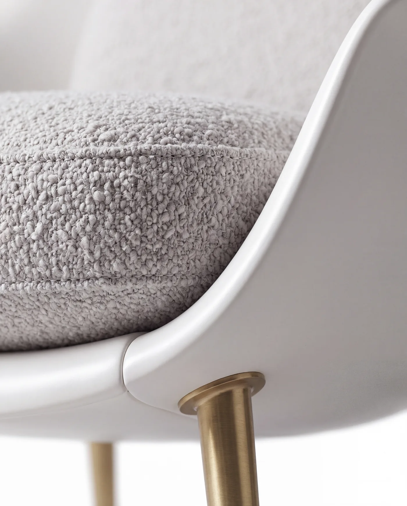 Close-up of the piped bouclé cushion, the lacquer edge and a brass leg socket