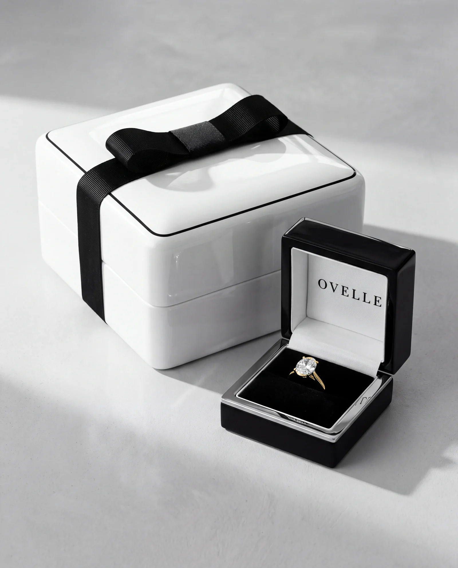 The white gift box with black ribbon beside the ring box