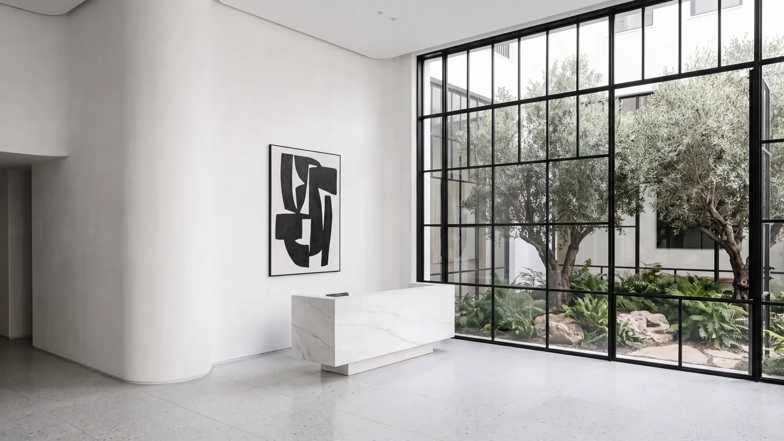 ALBA's garden lobby: white walls, a marble desk and steel windows onto olive trees